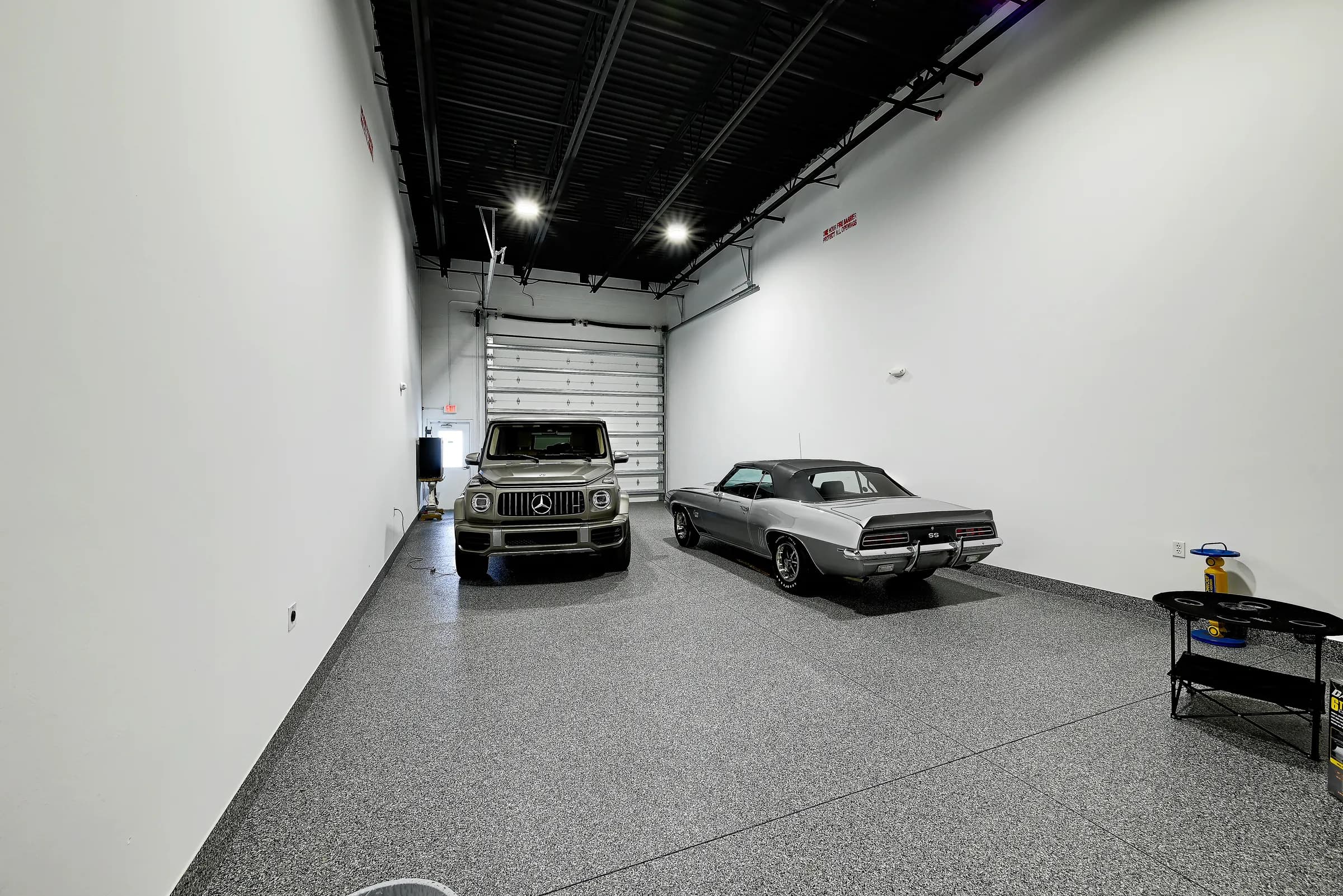 A classic muscle car and an SUV parked side by side inside a Vehicle Fortress unit